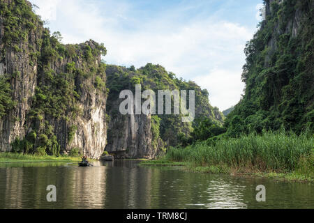 View of limestone mountain in valley with tourist cruising at evening, Ngo Dong river, Ninh Binh, Halong Bay on land Stock Photo