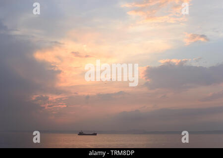 Beautiful cloudy sunset and sea landscape. Pink and gold colored sky in the evening. Stock Photo