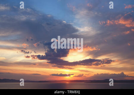 Beautiful cloudy sunset and sea landscape. Pink and gold colored sky in the evening. Stock Photo