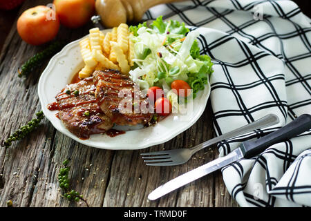 Pork steak with sauce in a white plate on a wooden table Stock Photo