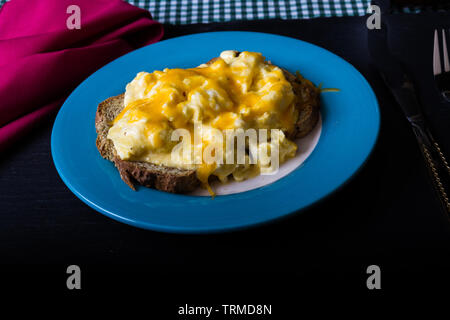 Scrambled eggs with melted grated cheese on toast Stock Photo