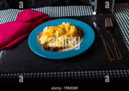 Scrambled eggs with melted grated cheese on toast with red napkin Stock Photo