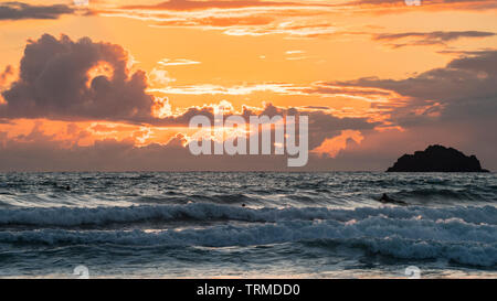A dramatic sky at dusk with an orange afterglow and dark clouds above a choppy sea. Cornwall, UK. Stock Photo