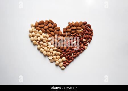 Almonds, hazelnuts and peanuts heart shaped composition isolated on white background from a high angle view Stock Photo