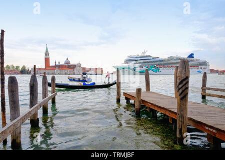 A large cruise departing from Venice sailing by San Giorgio Maggiore as seen from the waterfront with a gondola in the foreground, Italy Europe EU Stock Photo