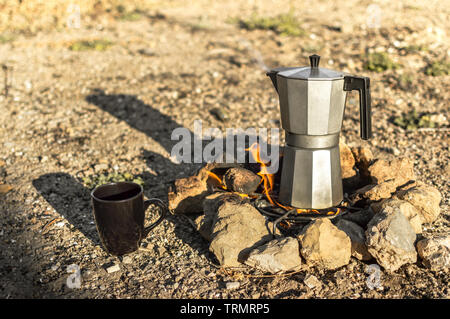 Preparing coffee with bonfire and moka pot coffee maker, resting during a  camp in nature. Overhead view of firewood burning, cup and coffee machine  Stock Photo - Alamy