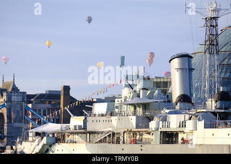 The floatilla from the RICOH Lord Mayor of London's Hot Air Balloon Regatta 2019 passes over HMS Belfast and Tower Bridge during early morning.