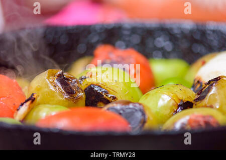 Cooking Mexican green sauce, salsa verde, made with tomatillos, tomatoes, onions, garlic chiles and cilantro. Sizzling pan and steaming vegetables, co Stock Photo
