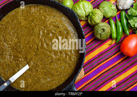 Cooking Mexican green sauce, salsa verde, made with tomatillos, tomatoes, onions, garlic chiles and cilantro. Sizzling pan and steaming vegetables, co Stock Photo