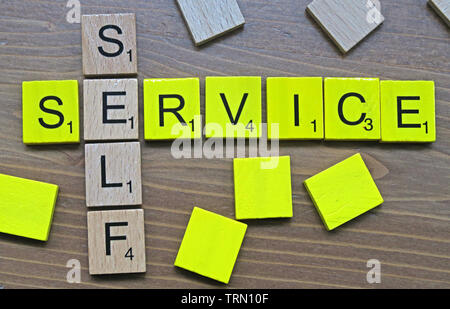 Self-Service - spelt out in yellow and wooden Scrabble letters Stock Photo