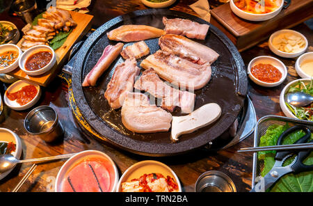 Pan-fried cooked black pork meal in Korea restaurant, fresh delicious korean food cuisine on iron plate with lettuce, close up, copy space, lifestyle Stock Photo