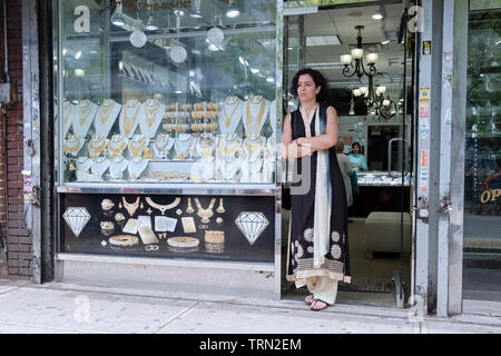 An attractive woman in a sari in deep thought outside the store where she works. Diversity Plaza, Jackson Heights, Queens, New York City. Stock Photo