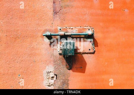 Old, iron, orange rusty metal door with lock and shutter Stock Photo