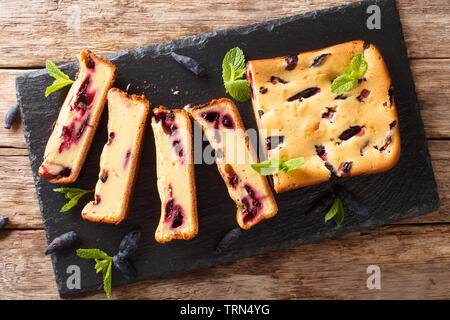 Sweet cake with honeysuckle sliced on the board closeup on the table. horizontal top view from above Stock Photo