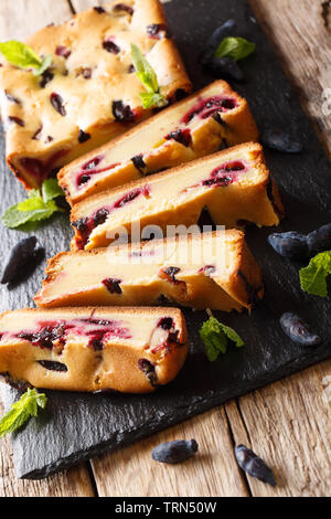 Sweet cake with honeysuckle sliced on the board closeup on the table. vertical Stock Photo