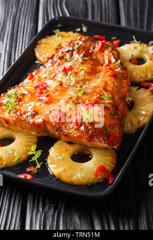 Red fish fillet baked with pineapple in chili sweet sauce close-up on a plate on the table. vertical Stock Photo