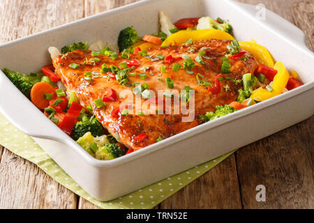 Close up of baked salmon with pepper, broccoli, cauliflower and carrot in a baking dish on the table. horizontal Stock Photo