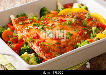 Red fish fillet baked with vegetables, spices and herbs close-up in a baking dish on the table. horizontal Stock Photo