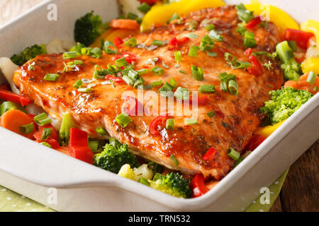 baked salmon with summer vegetables close-up in a baking dish on the table. horizontal Stock Photo