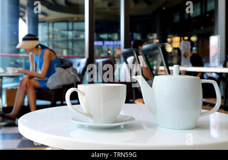 White porcelain tea set served on cafe's round table Stock Photo