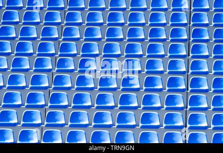 Empty blue plastic chairs in a row at the football stadium Stock Photo