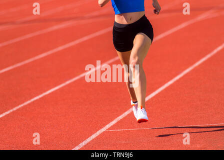Young sporty woman running on sunny day Stock Photo