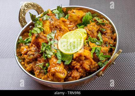Indian chicken curry close up view, hot delicious indian homemade chicken served in authentic copper bowl. Stock Photo