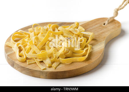Homemade tagliatelle on cutting board on rustich wooden white background Stock Photo