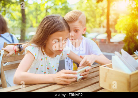 Children playing with mobile phone at terrace, addicted to gadget Stock Photo