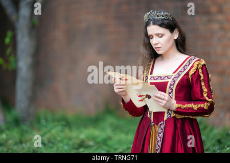 Woman in renaissance dress reading a letter Stock Photo