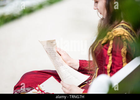 Woman in renaissance dress reading a letter. Small depth of field, focus is on the list Stock Photo