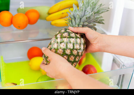 Woman getting a pineapple from fridge. Close up. Stock Photo