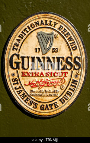 Old metal Guinness enamel sign - Guinness extra stout advertising vintage sign board on wall. Stock Photo