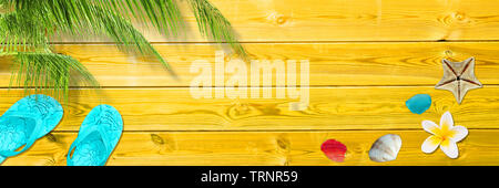 Palm leaf, flip flops and seashells on yellow wooden planks, panoramic beach and summer background with copy space Stock Photo