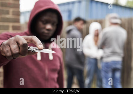 Teenage Boy In Urban Gang Pointing Knife Towards Camera Stock Photo