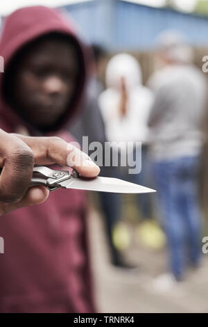 Teenage Boy In Urban Gang Pointing Knife Towards Camera Stock Photo