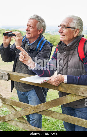 Two Retired Male Friends On Walking Holiday Looking Through Binoculars Stock Photo
