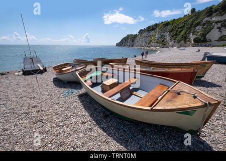 Wooden boats washed up on shingle beach at Beer, South Devon, UK. Stock Photo