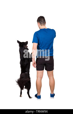 Rear view full length of young man owner training his obedient border collie dog standing on hind paws isolated over white background. Human and pet f Stock Photo