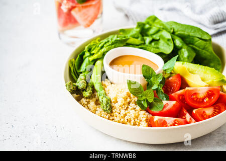Green salad with quinoa, avocado and asparagus in a white bowl. Vegan food concept. Stock Photo