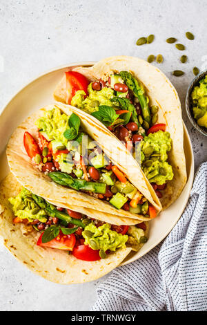 Vegan tortilla wraps with quinoa, asparagus, beans, vegetables and guacamole. Stock Photo
