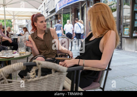 Belgrade, Serbia, June 6th 2019: Street scene with two young women sitting in outdoor cafe Stock Photo