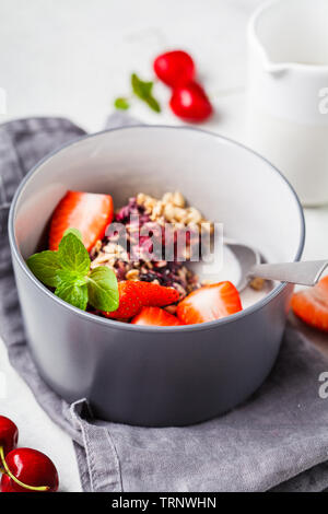 Baked oatmeal with berries and milk in a gray bowl. Vegan breakfast. Stock Photo