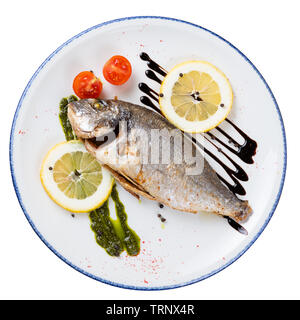 Dorado fried fish on a round plate with a blue border, top view on an isolated background Stock Photo
