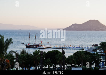 Aerial view of wooden pier with harbor, pirate tourist ship and marina in Turkey resort near Bodrum in sunset light. Stock Photo