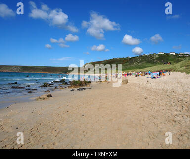 A sunny summers day on the beach in Sennen Cove, Cornwall, England, UK showing the sandy beach and blue sea under a blue sky. Stock Photo