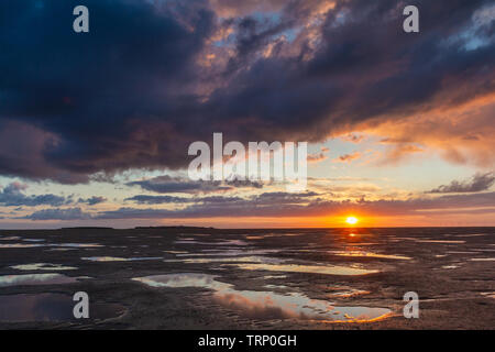 The sun setting over Hilbre Island and Liverpool Bay at the mouth of the Dee Estuary, Merseyside, England Stock Photo