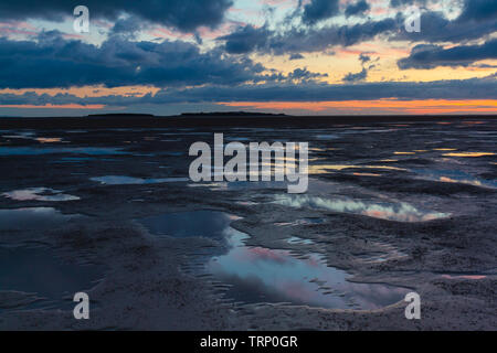 The sun setting over Hilbre Island and Liverpool Bay at the mouth of the Dee Estuary, Merseyside, England Stock Photo