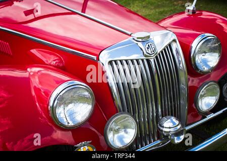 Bright red front end of an historic classic vintage MGA sports car showing headlights, radiator grille MG badge and brightwork. Stock Photo
