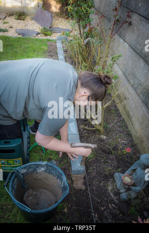 Young woman building a wall in a garden Stock Photo